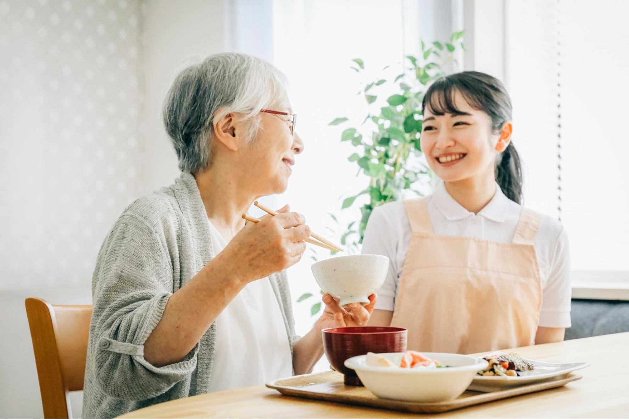 食事する高齢者と介護士
