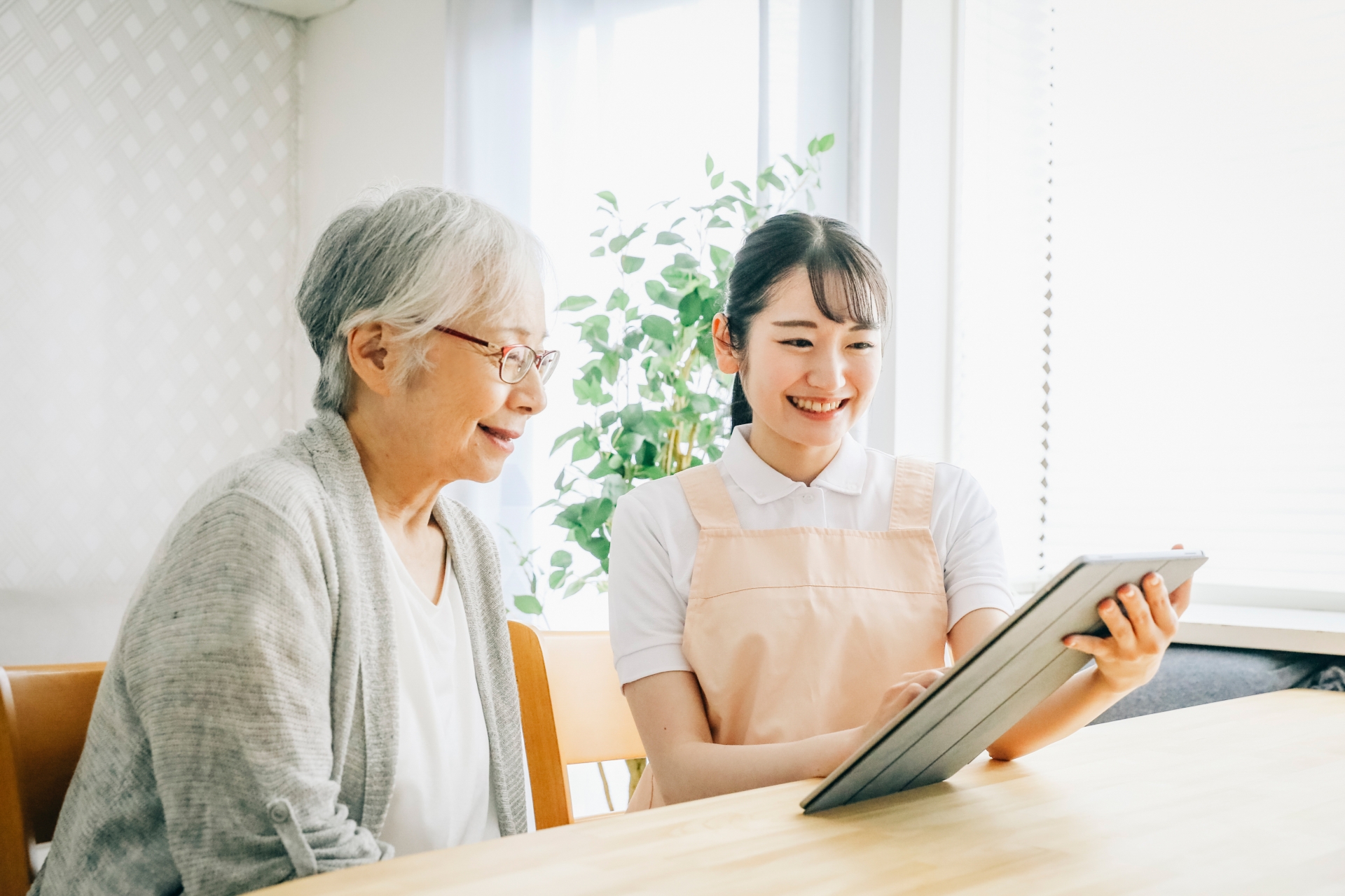 タブレットを使う介護士と高齢者女性