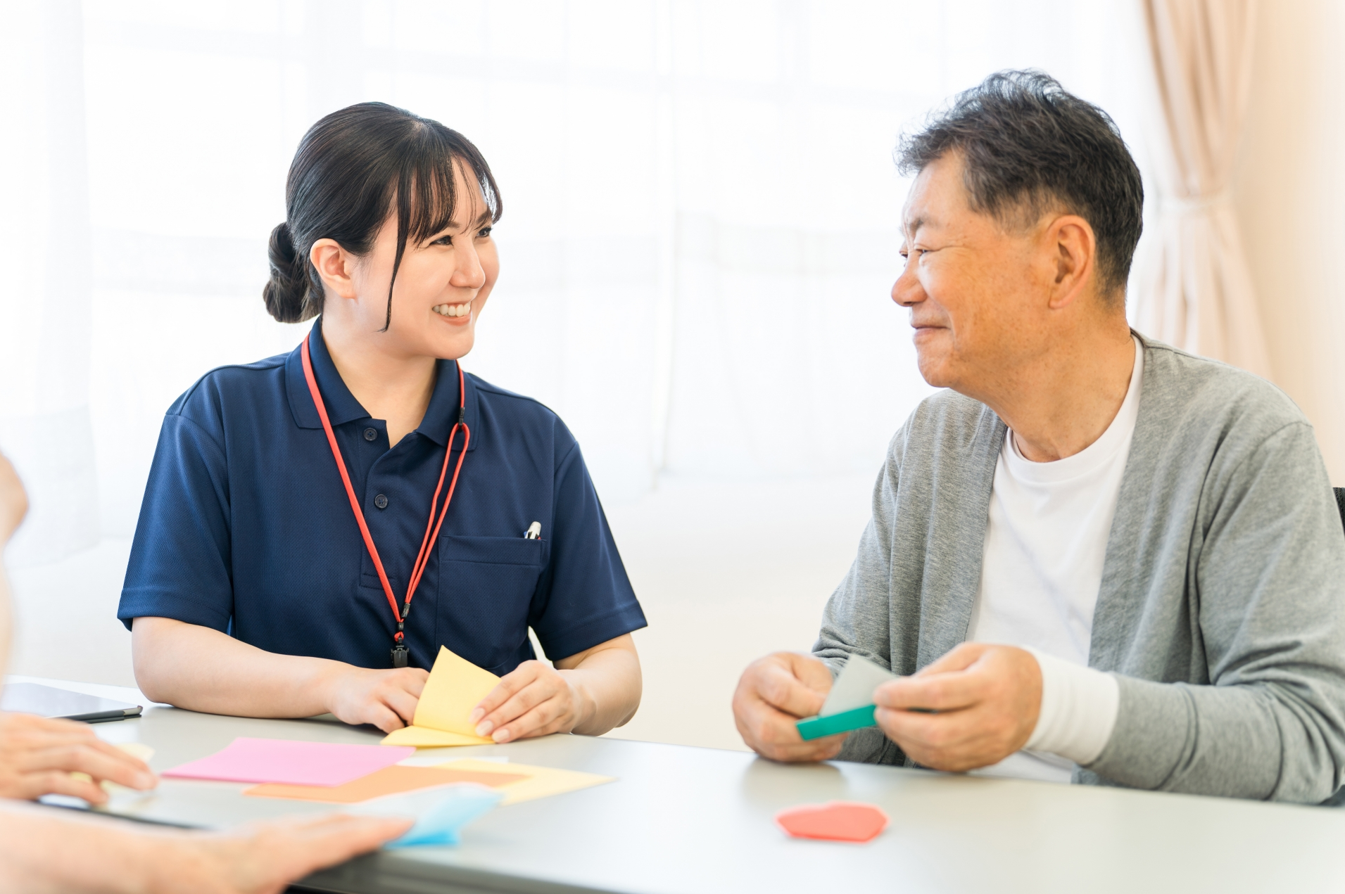 女性介護スタッフと折り紙をするシニア男性