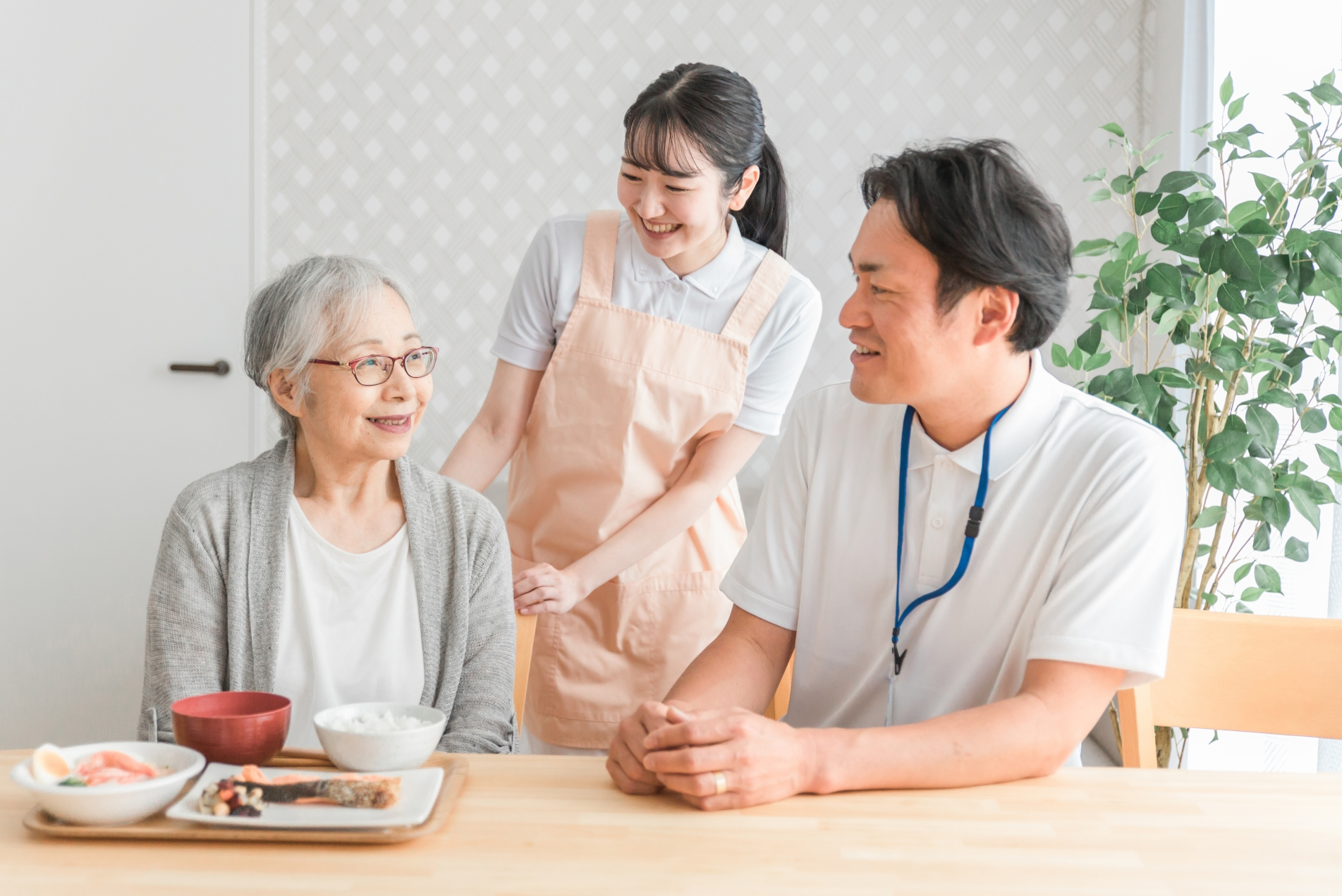 食事する高齢者と男女のスタッフ