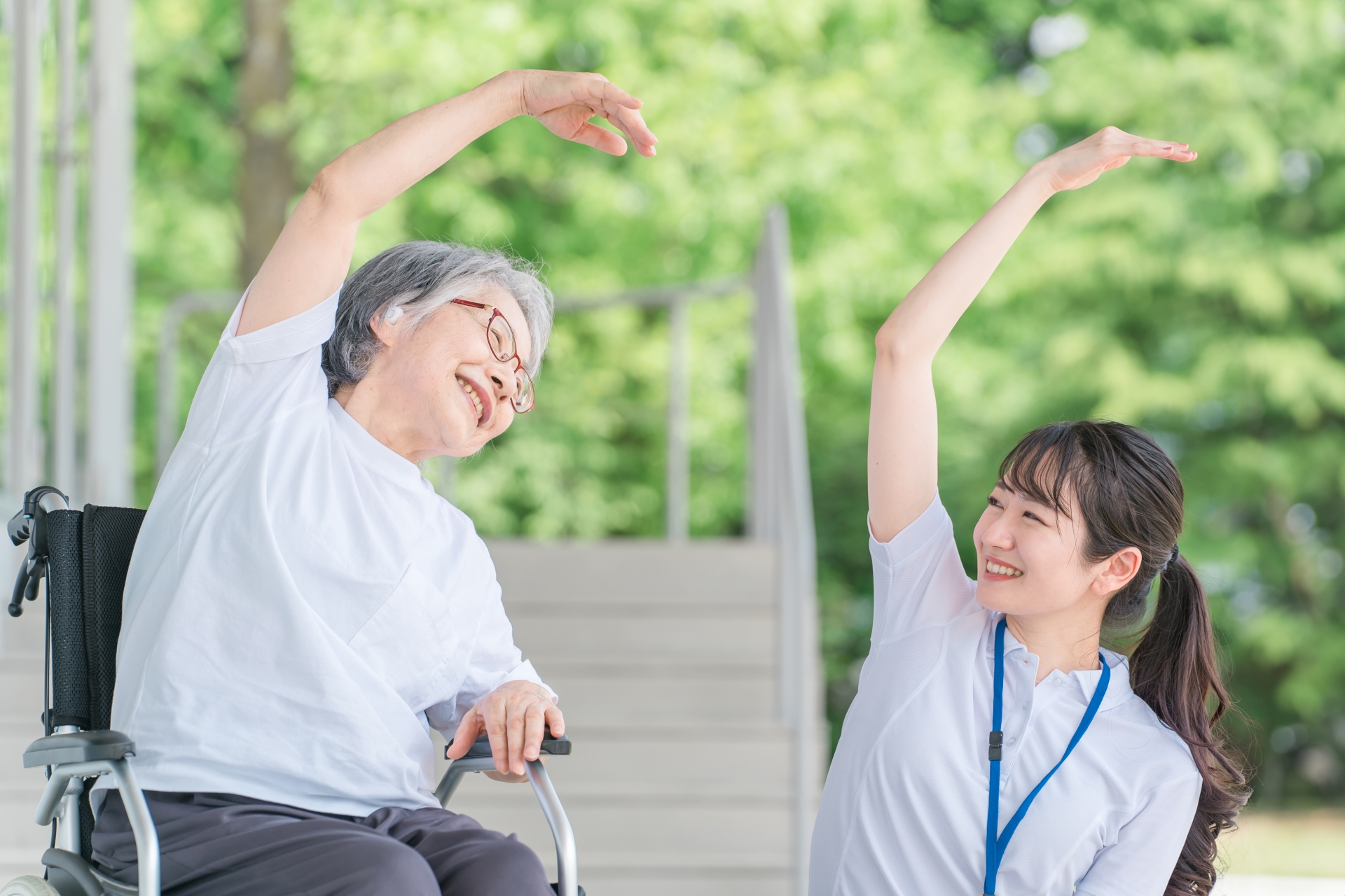 体操する車椅子に乗った高齢者と介護士