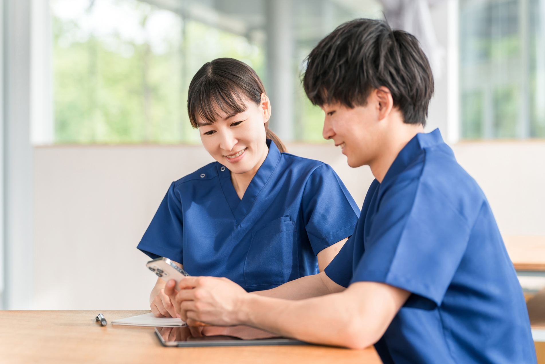 スマホを見ながら会話する先輩と若い看護師