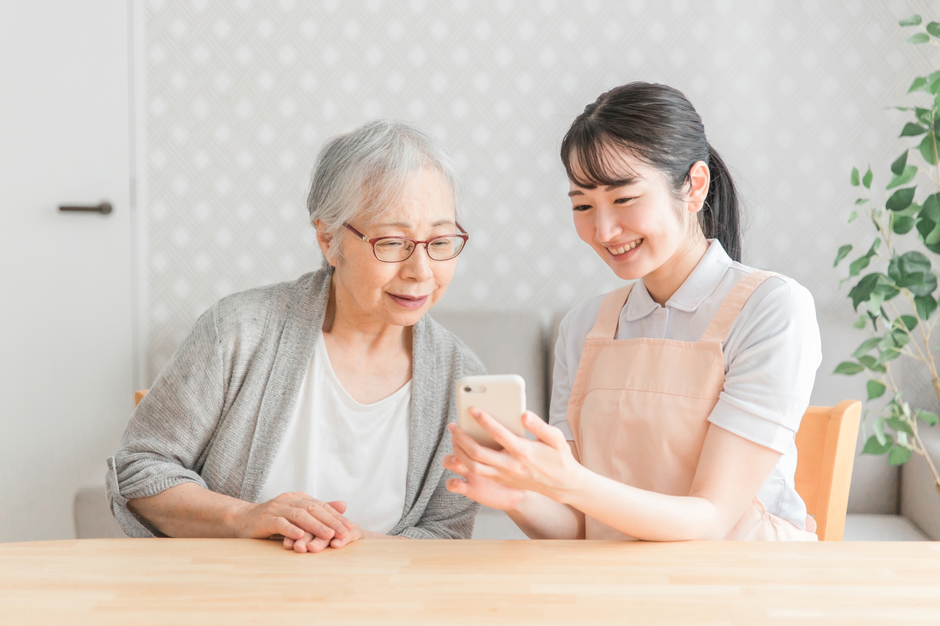 スマホを使う高齢者と女性スタッフ