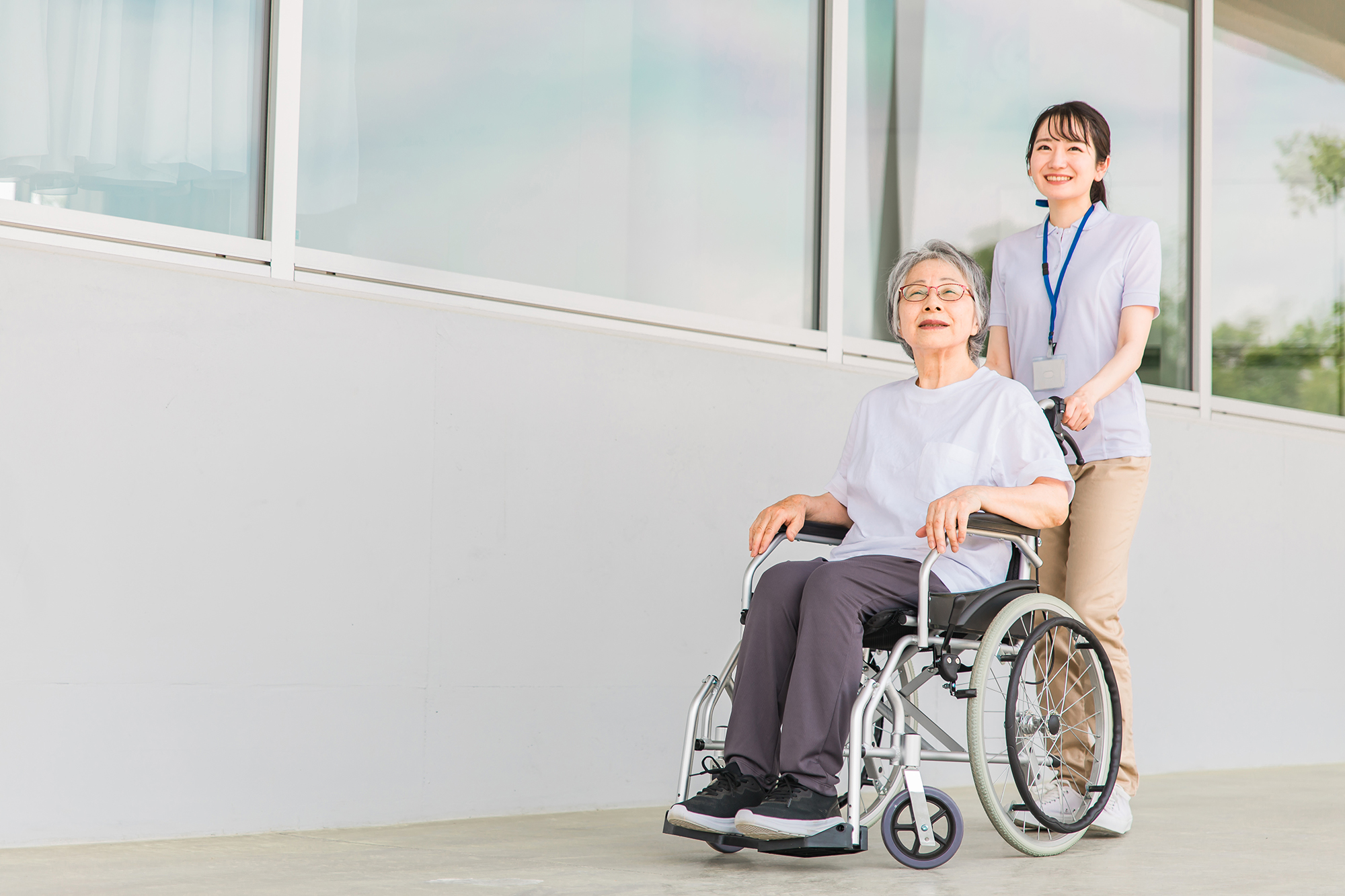 病院で散歩する車椅子に乗る高齢者と介護士
