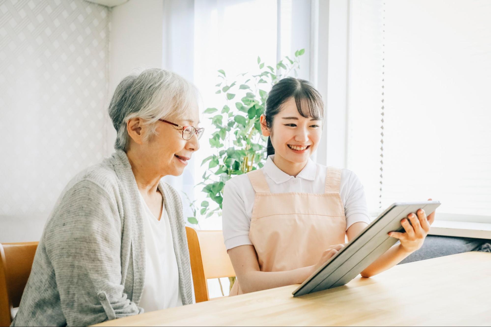 タブレットを使う介護士と高齢者女性