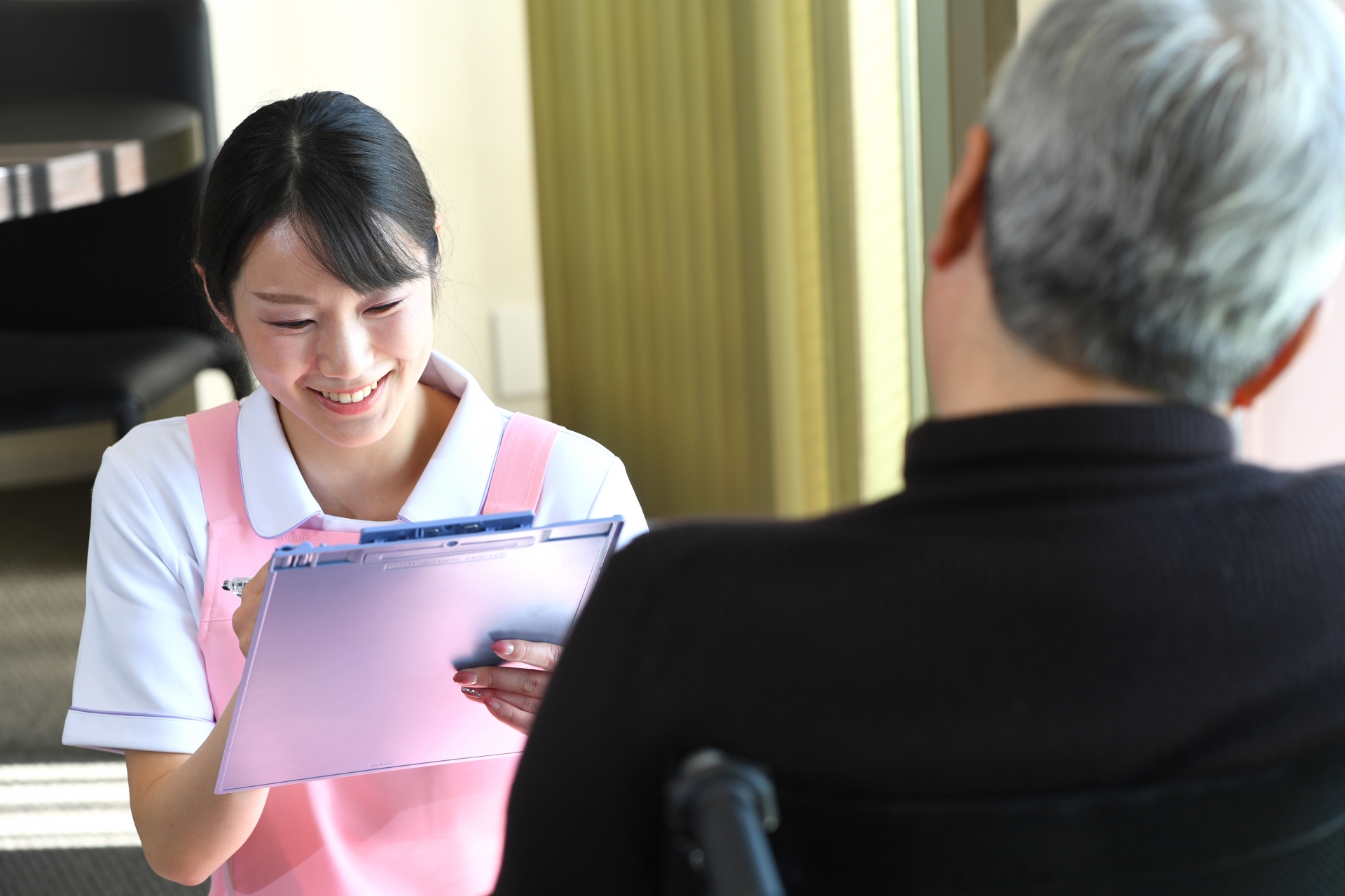 カウンセリング（問診）をする女性の介護士とシニアの男性