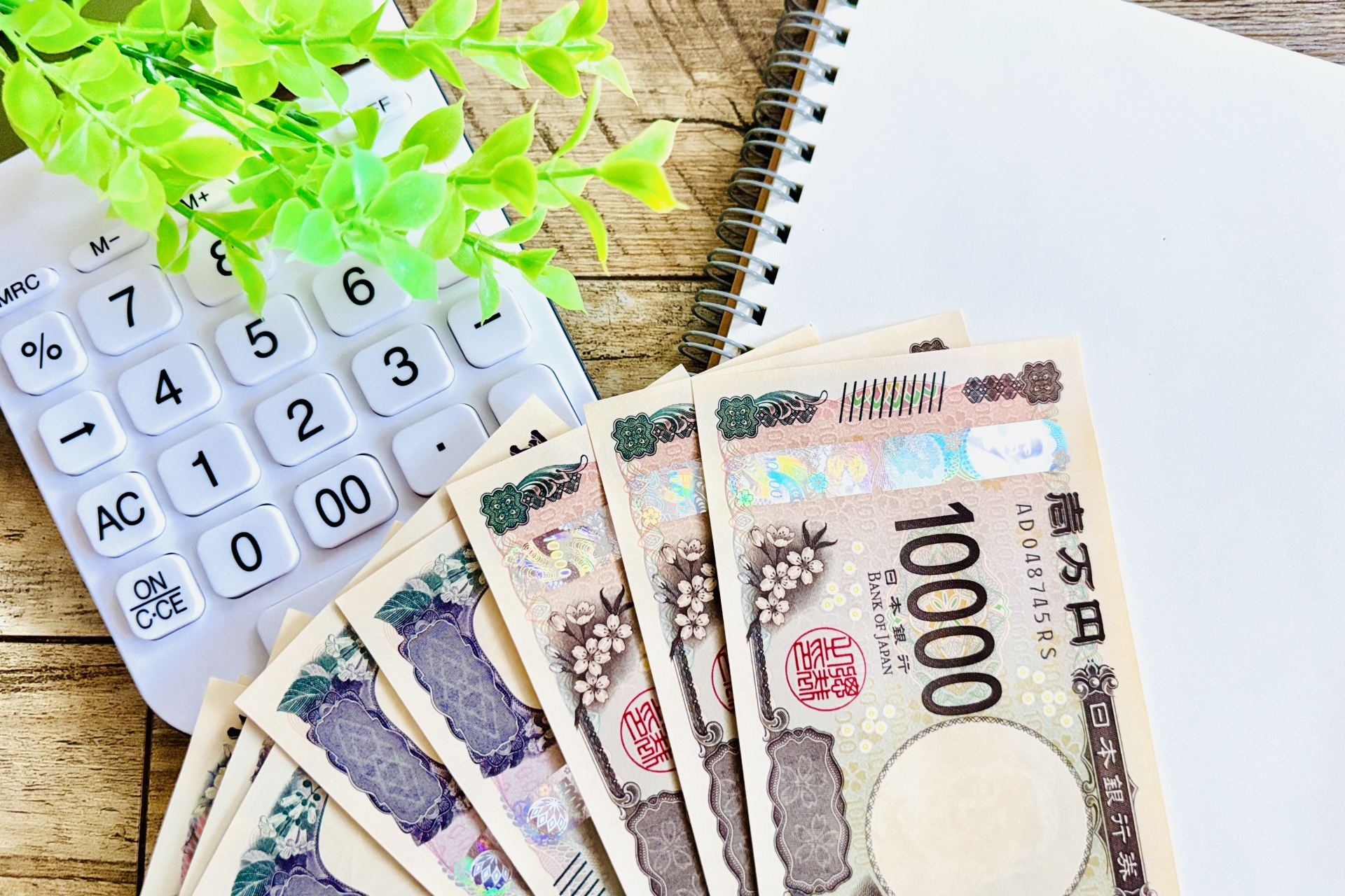 白い電卓と一万円とノート