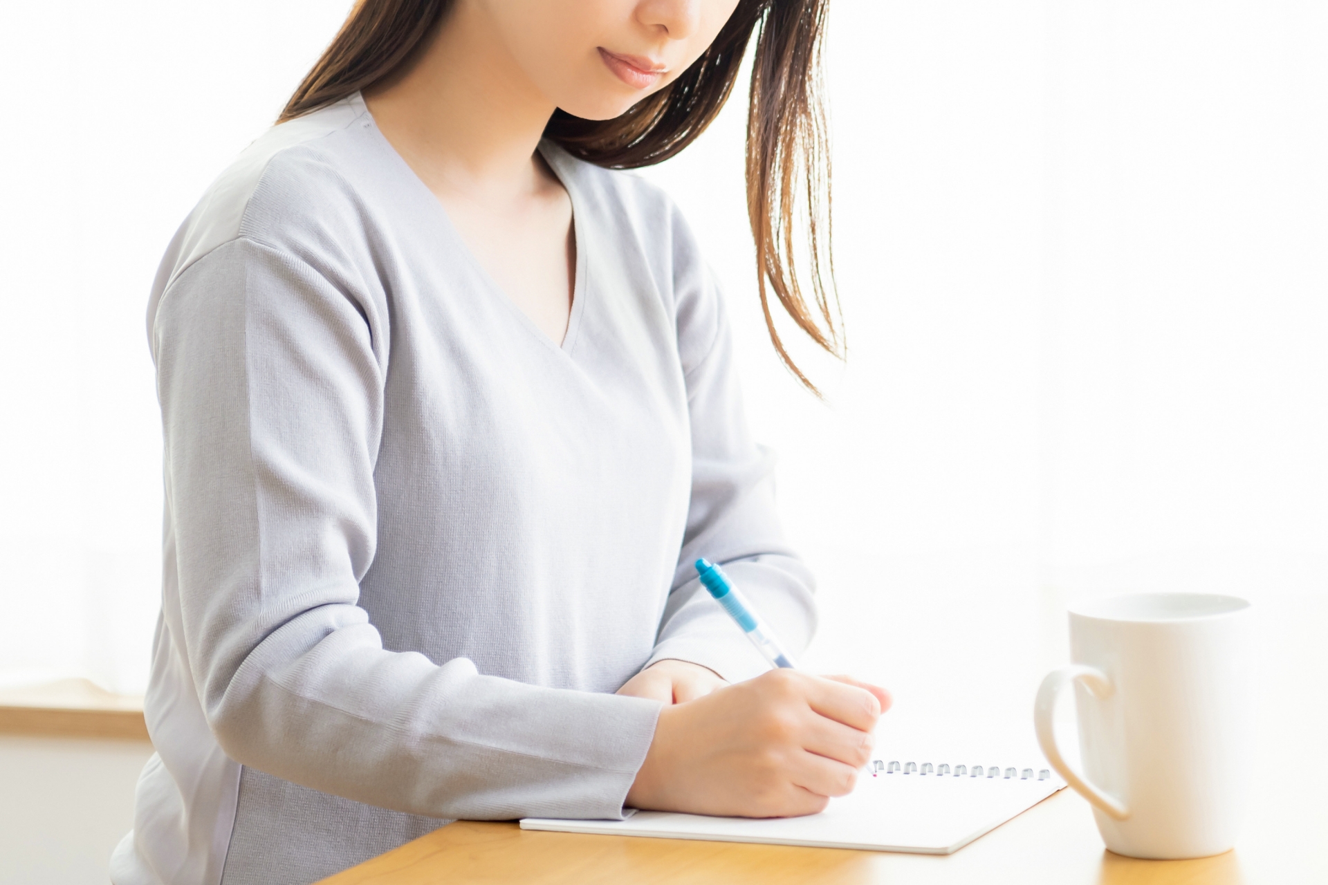 ノートにメモを書く若い女性