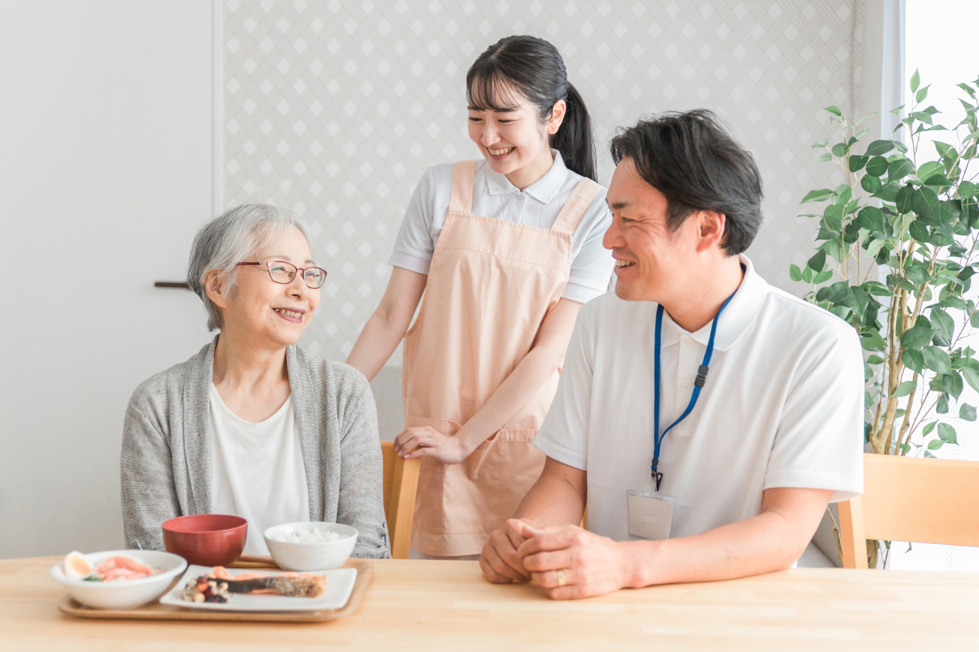 食事する高齢者と男女のスタッフ