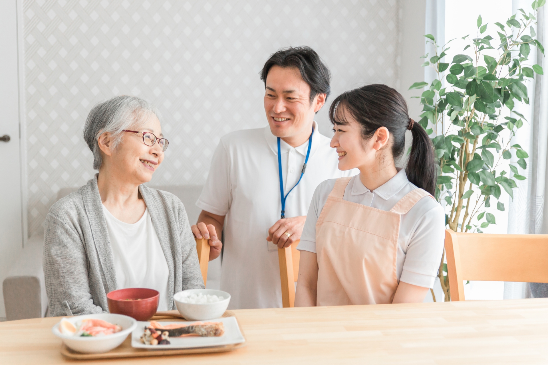 食事する高齢者と男女のスタッフ