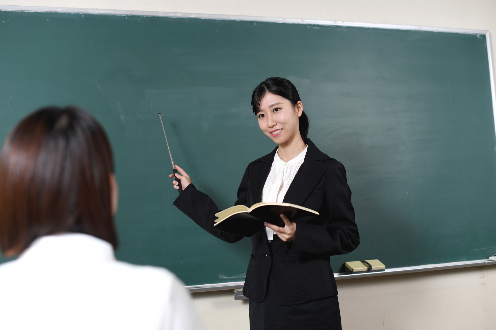 黒板の前で授業をするアジア人の女性教師
