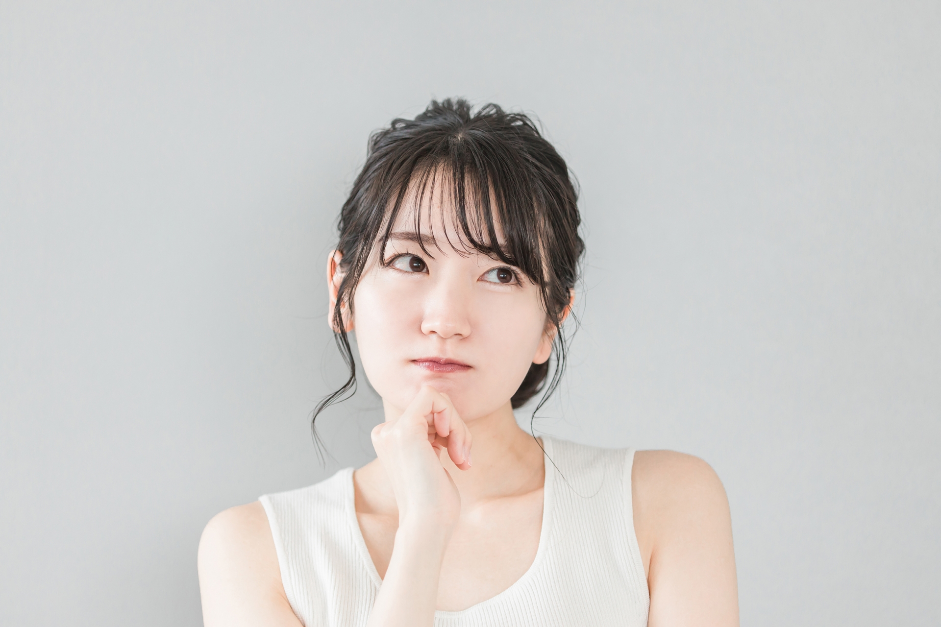 頬杖をついて考える・悩むアジア人女性