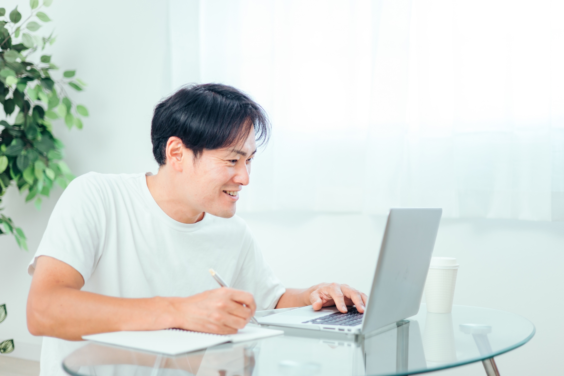 家でパソコンを使って勉強する男性（笑顔）