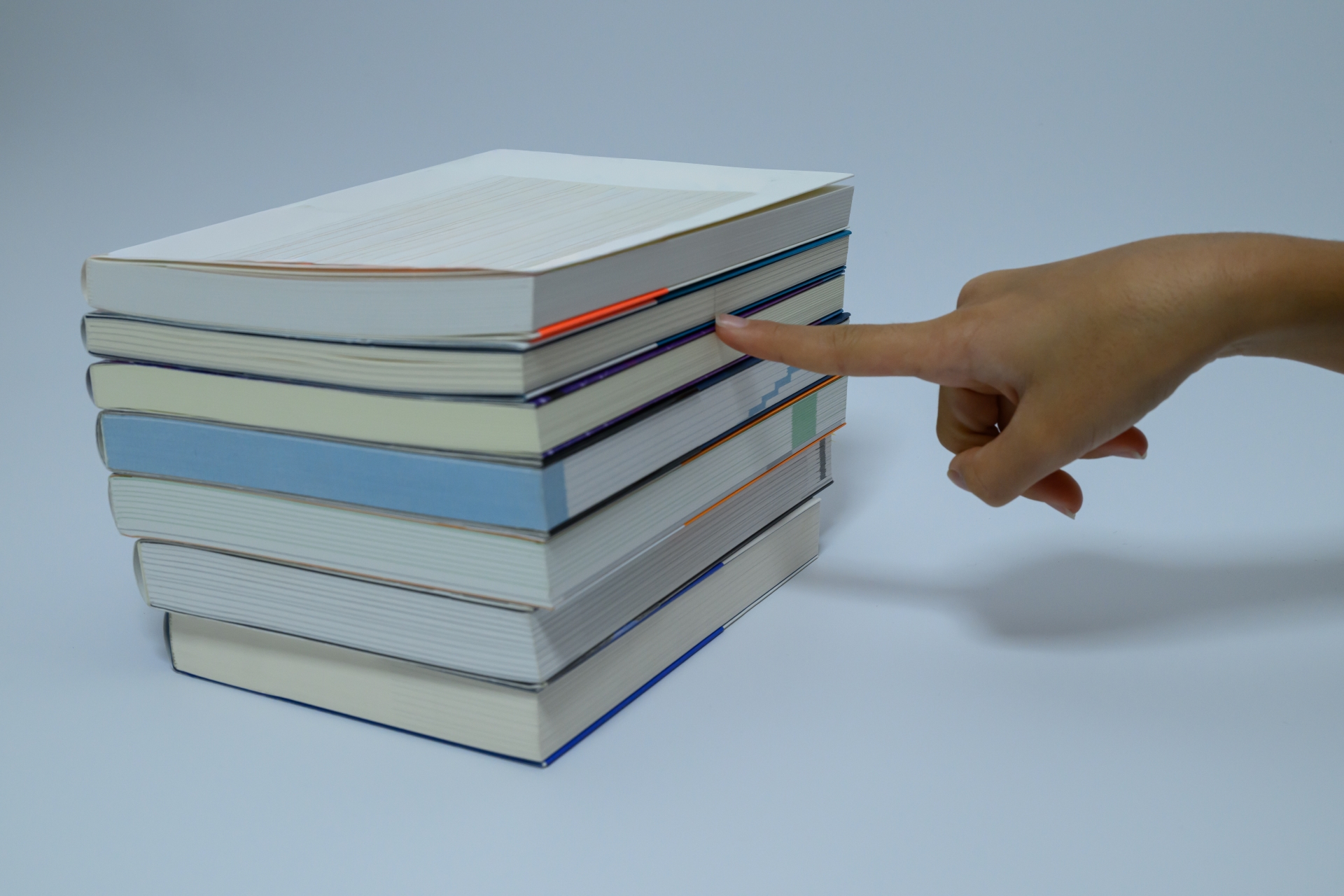 積まれた本の一冊を指差す手