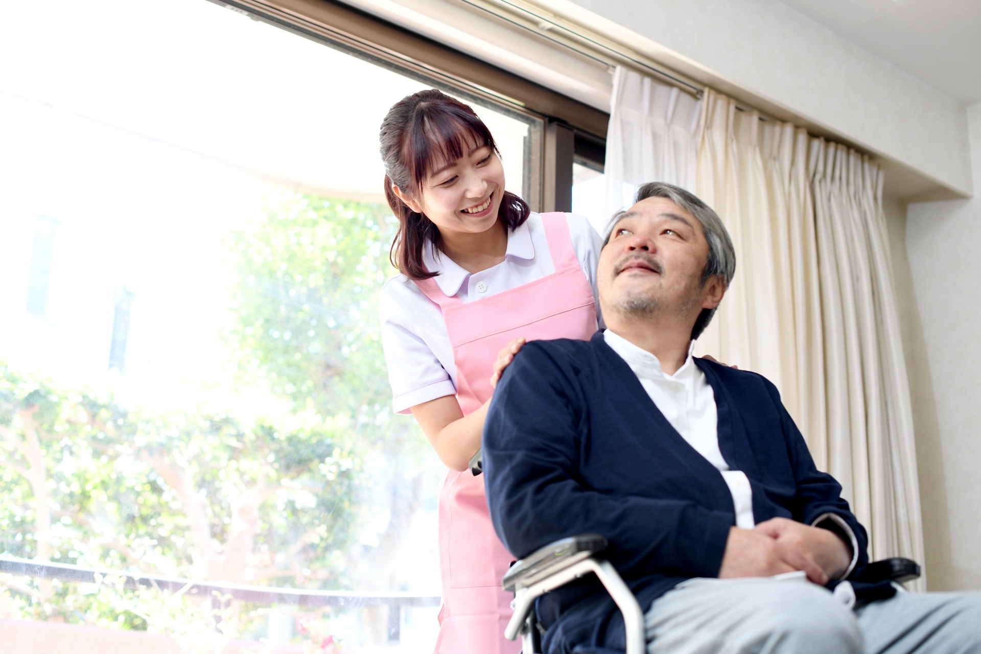 車椅子に乗る高齢者男性と女性の介護士
