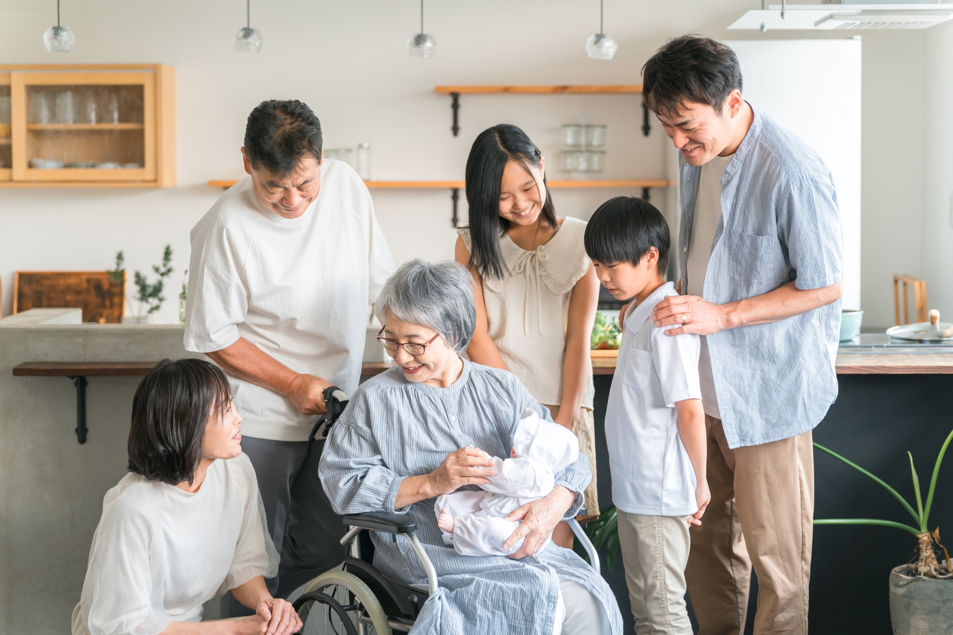 赤ちゃんと対面する高齢者女性と子供達