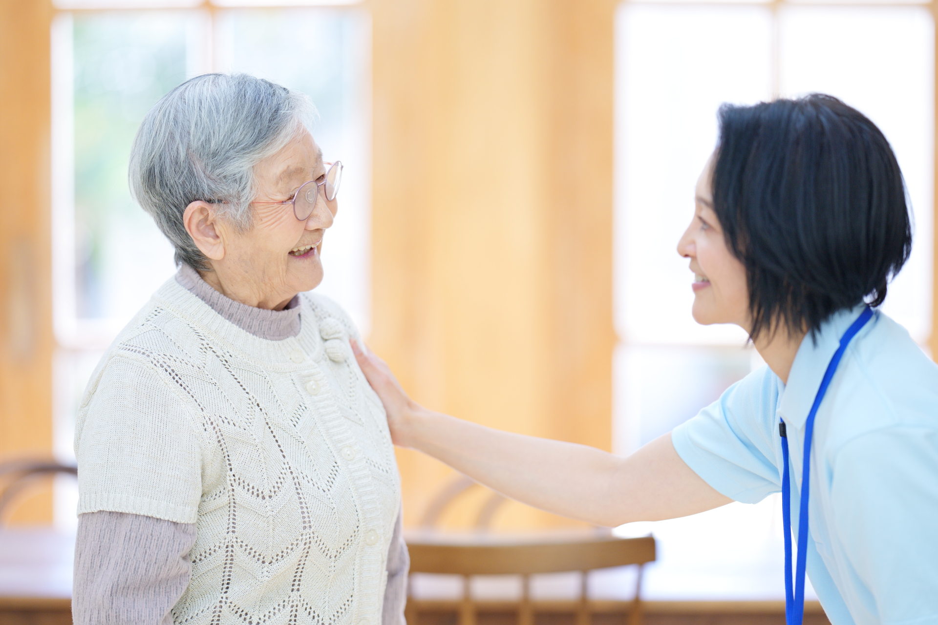 肩に手を置いて話している介護士と高齢女性