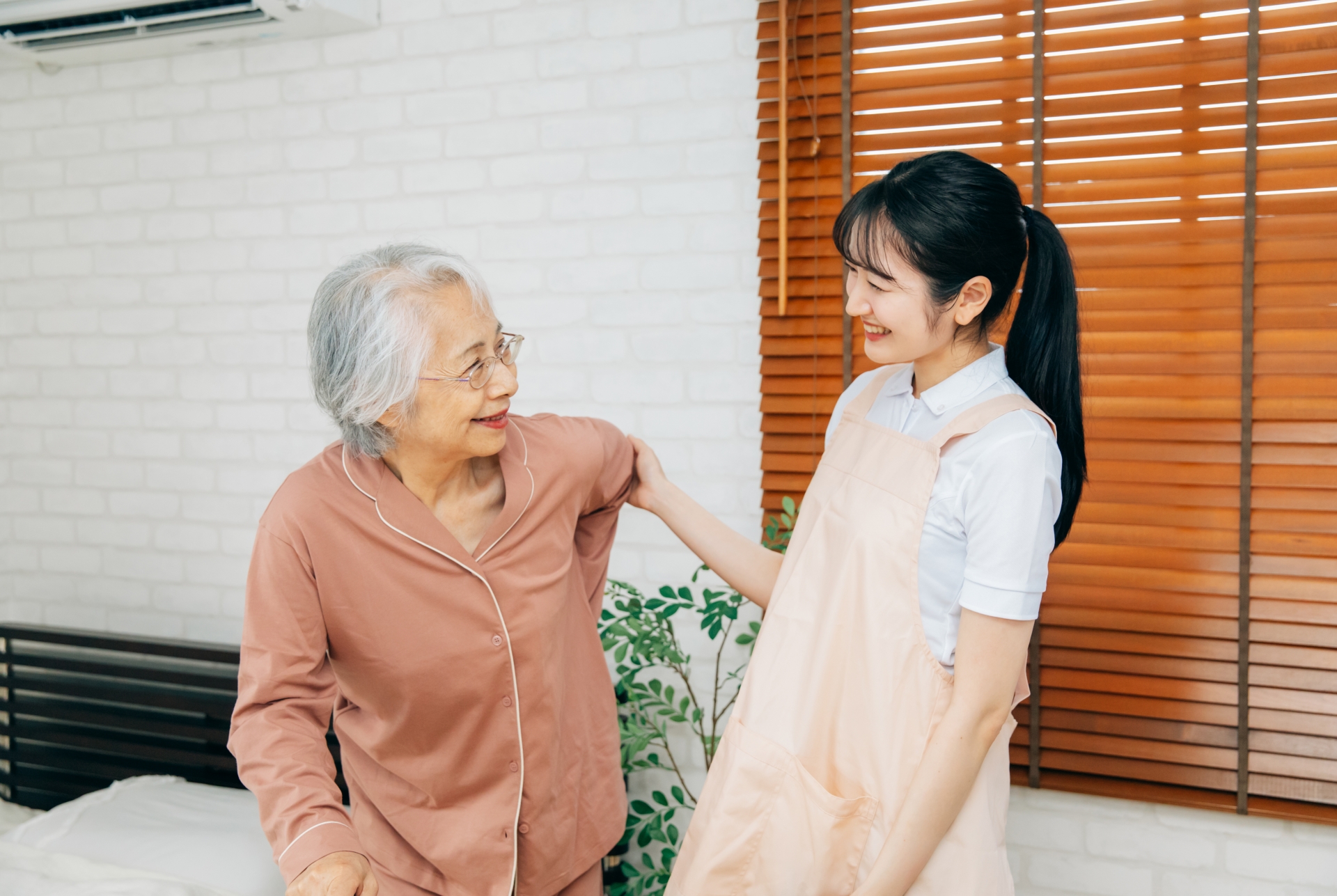 笑顔の高齢者女性と女性スタッフ（杖）