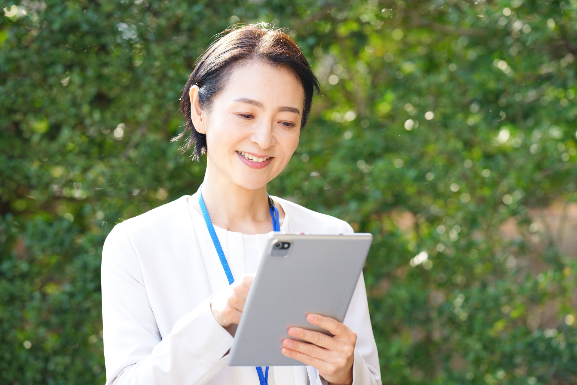 屋外でタブレットを使う笑顔のケアマネジャー