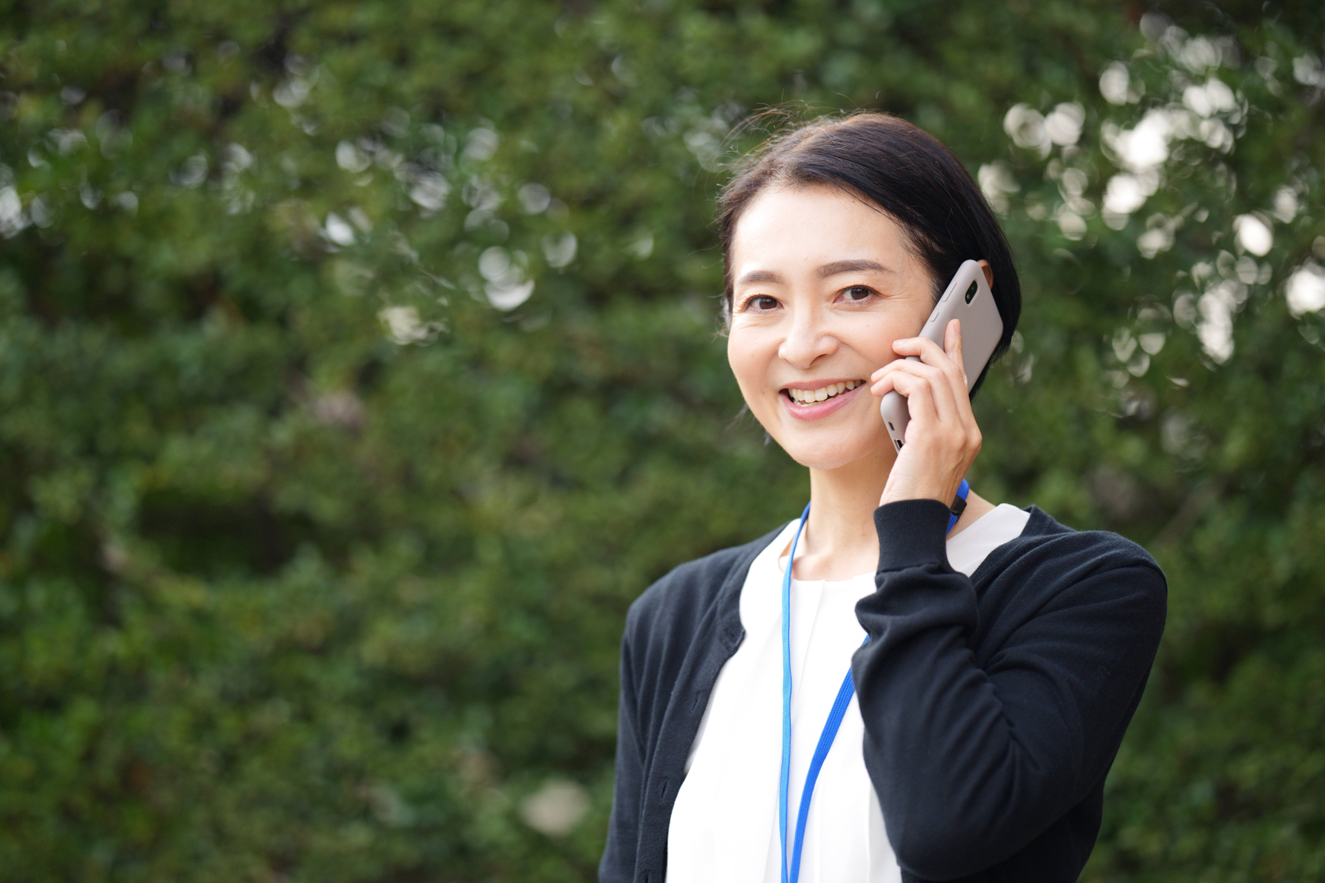 屋外でスマートフォンで電話しているカメラ目線のケアマネジャー