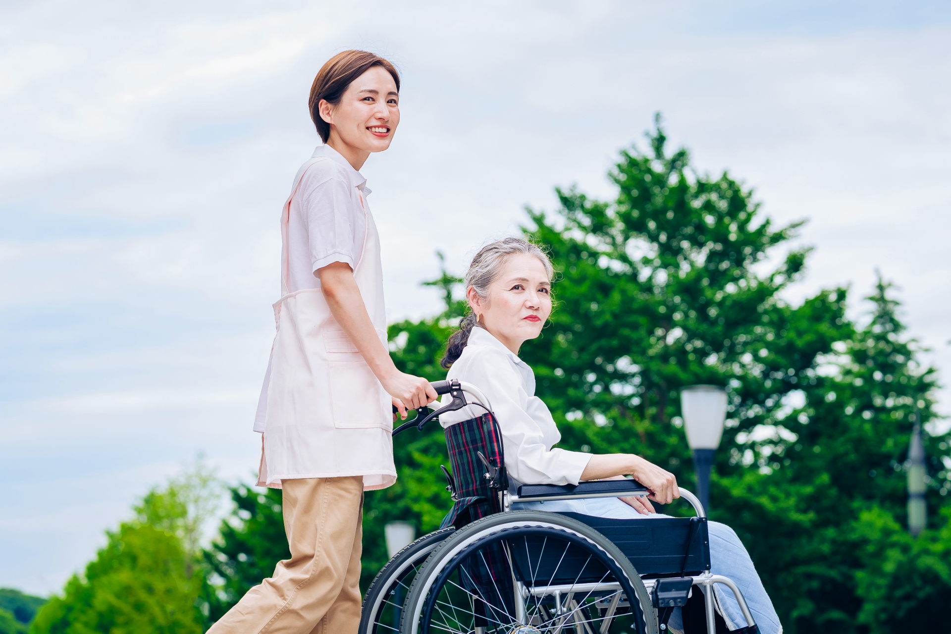 車椅子の女性と介護するエプロン姿の女性