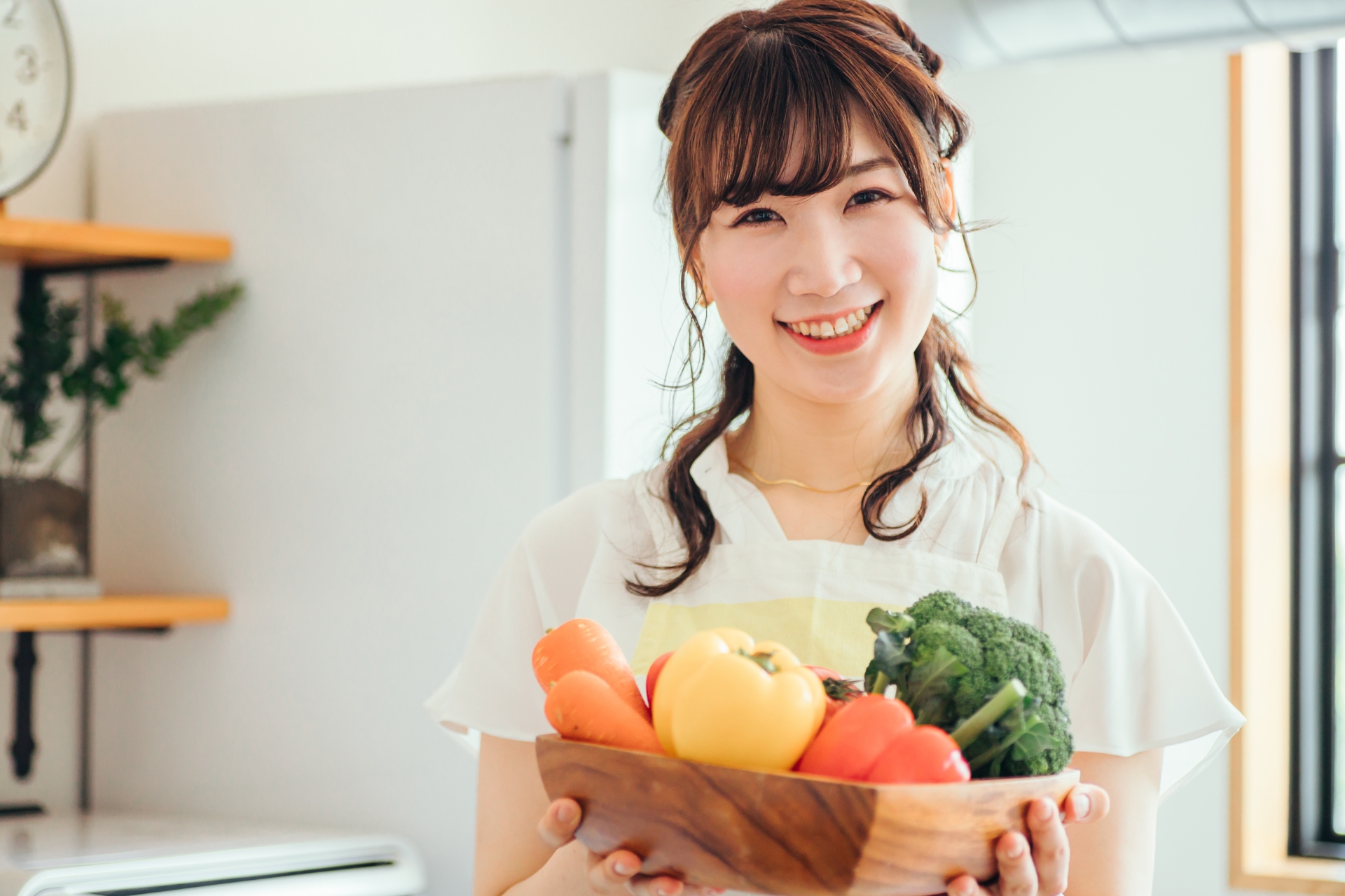 キッチンで野菜を持つ女性(笑顔)