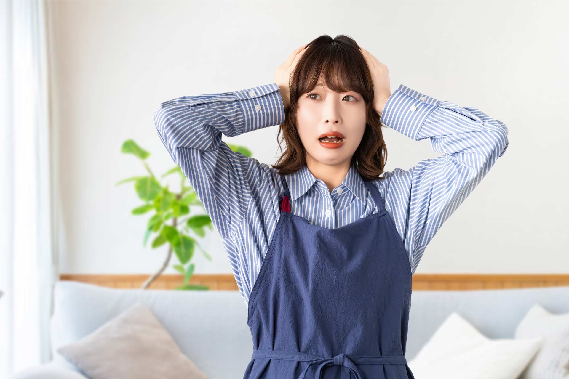頭を抱えて悩むエプロン姿の女性