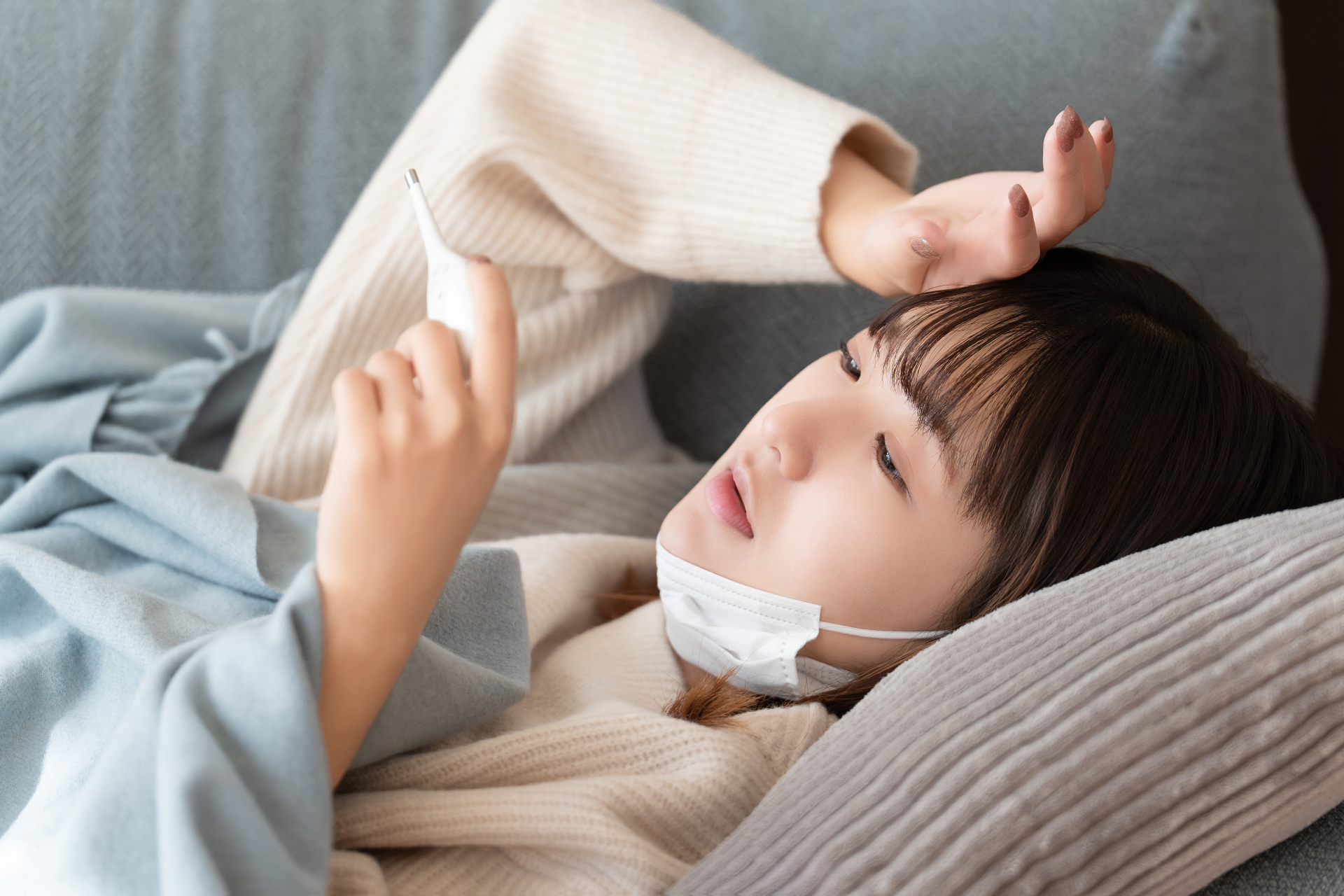 熱を測る体調不良の女性