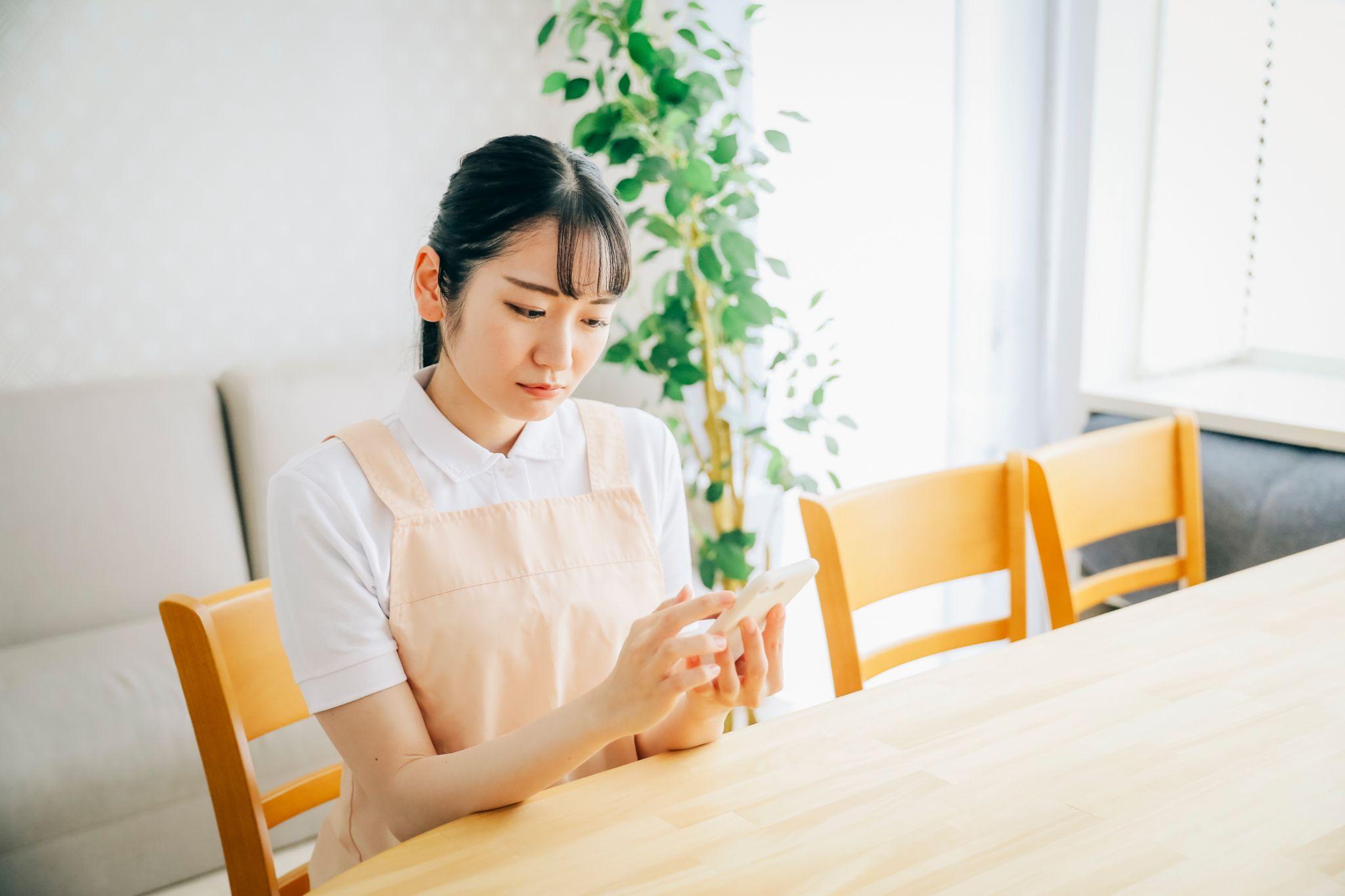スマホを使うエプロン姿の女性（困る）