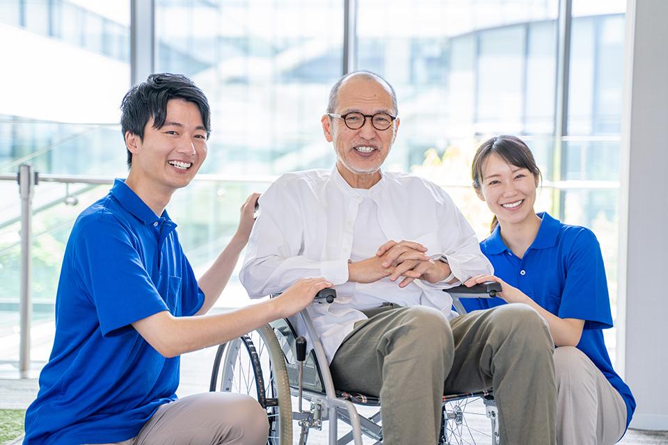 介護施設のシニア男性と男女のケアスタッフ