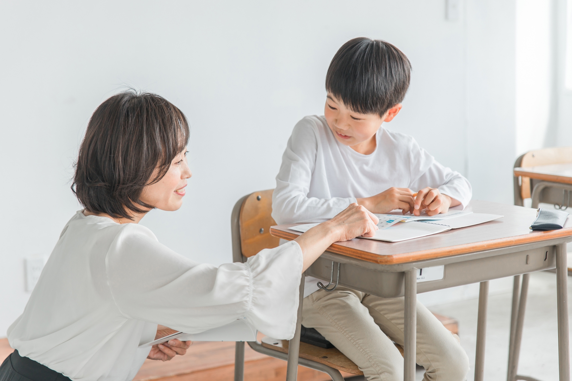 勉強する子供と指導する先生（個別指導）