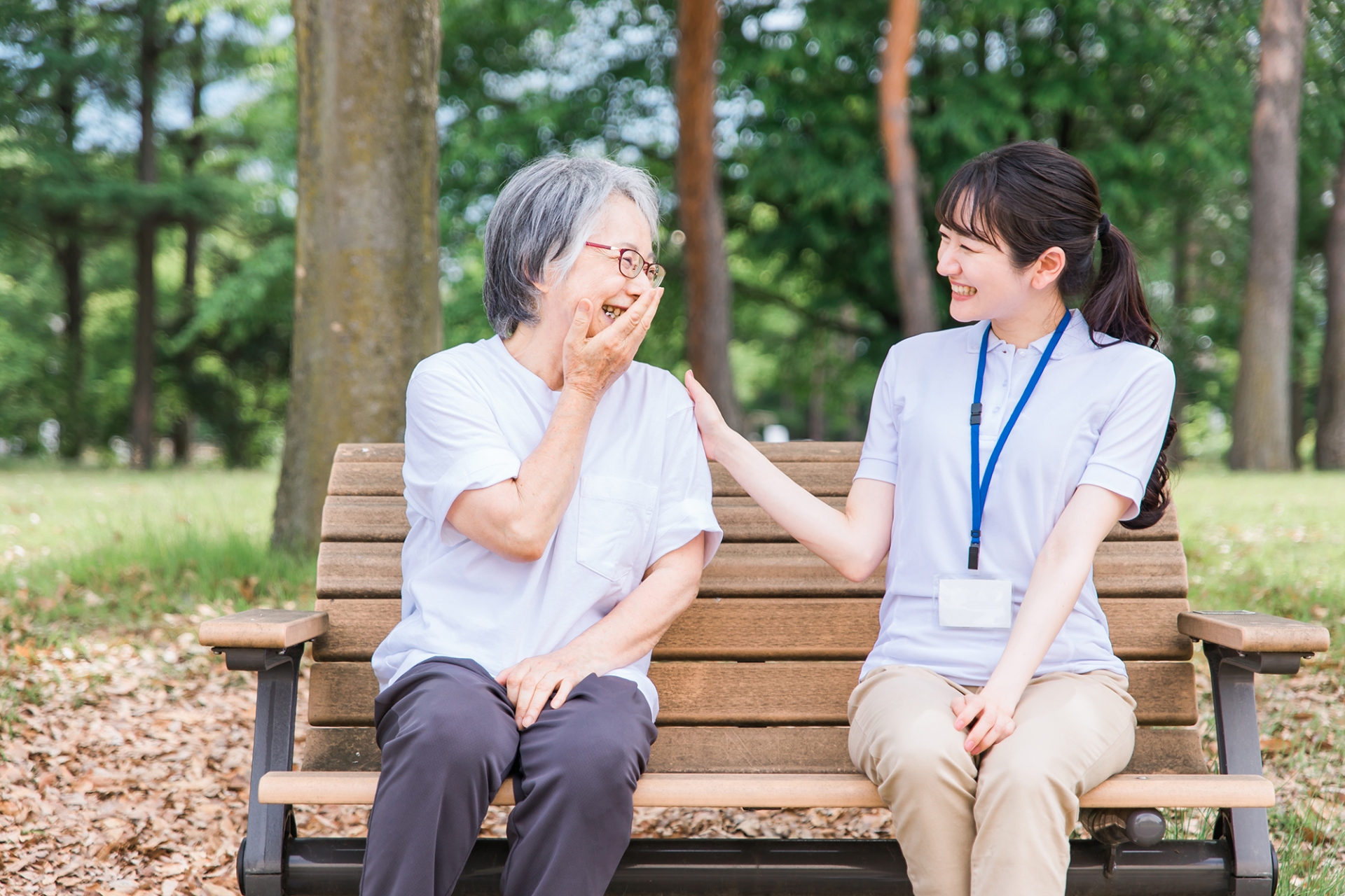公園で話す高齢者と笑顔の介護スタッフ女性