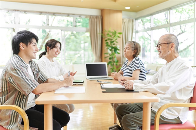 笑顔で会話する若夫婦と老夫婦