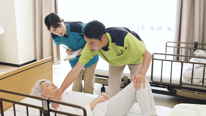 体位変換の指導を行うアジア人介護士