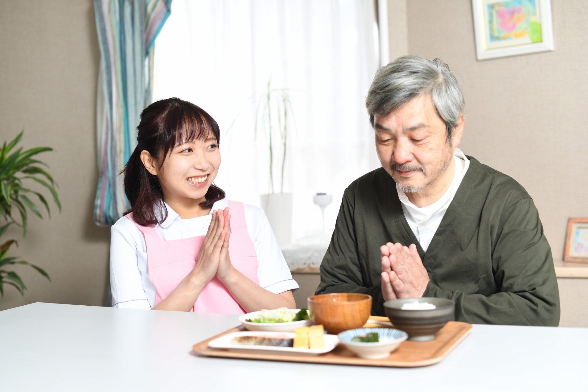 食事をする高齢者男性とエプロン姿の女性介護士