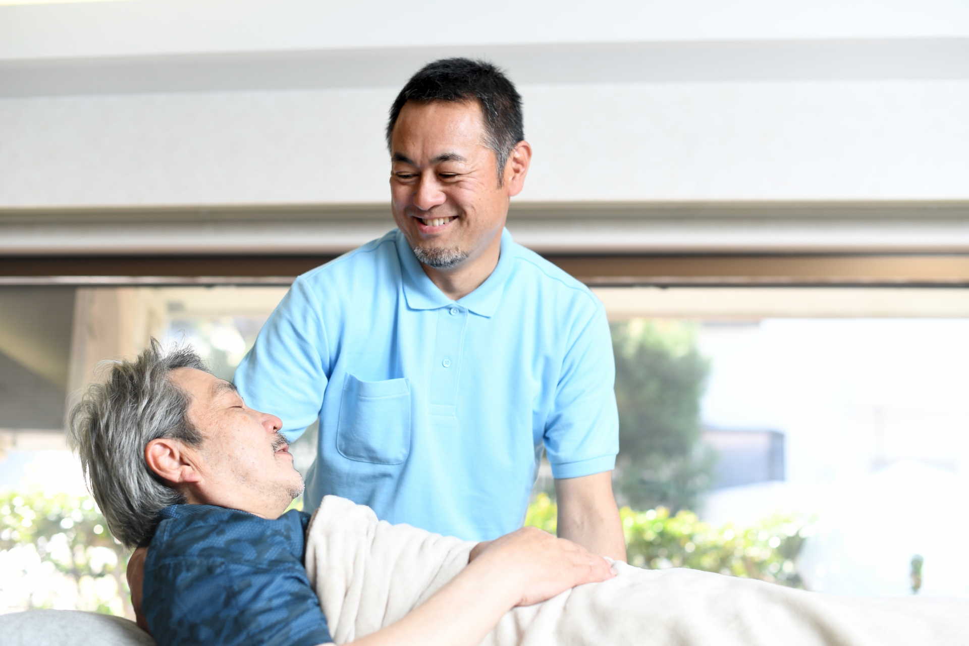 高齢者をベッドで介助する男性介護士