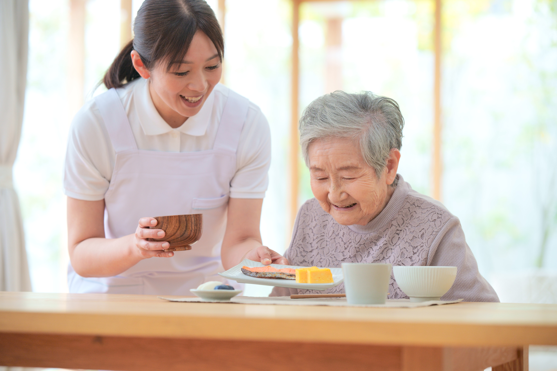 食事を運んでもらう高齢女性