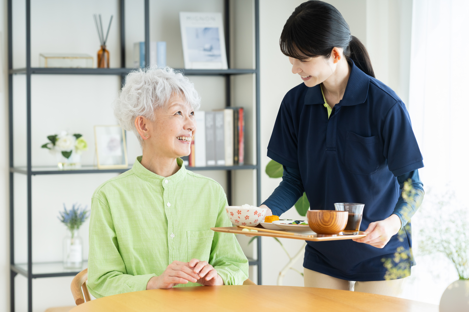 食事をするシニアの女性と介護福祉士