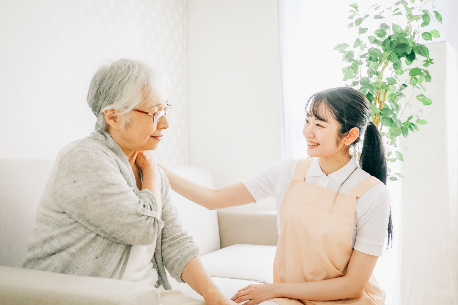 訪問介護する女性と高齢者(肩こり)