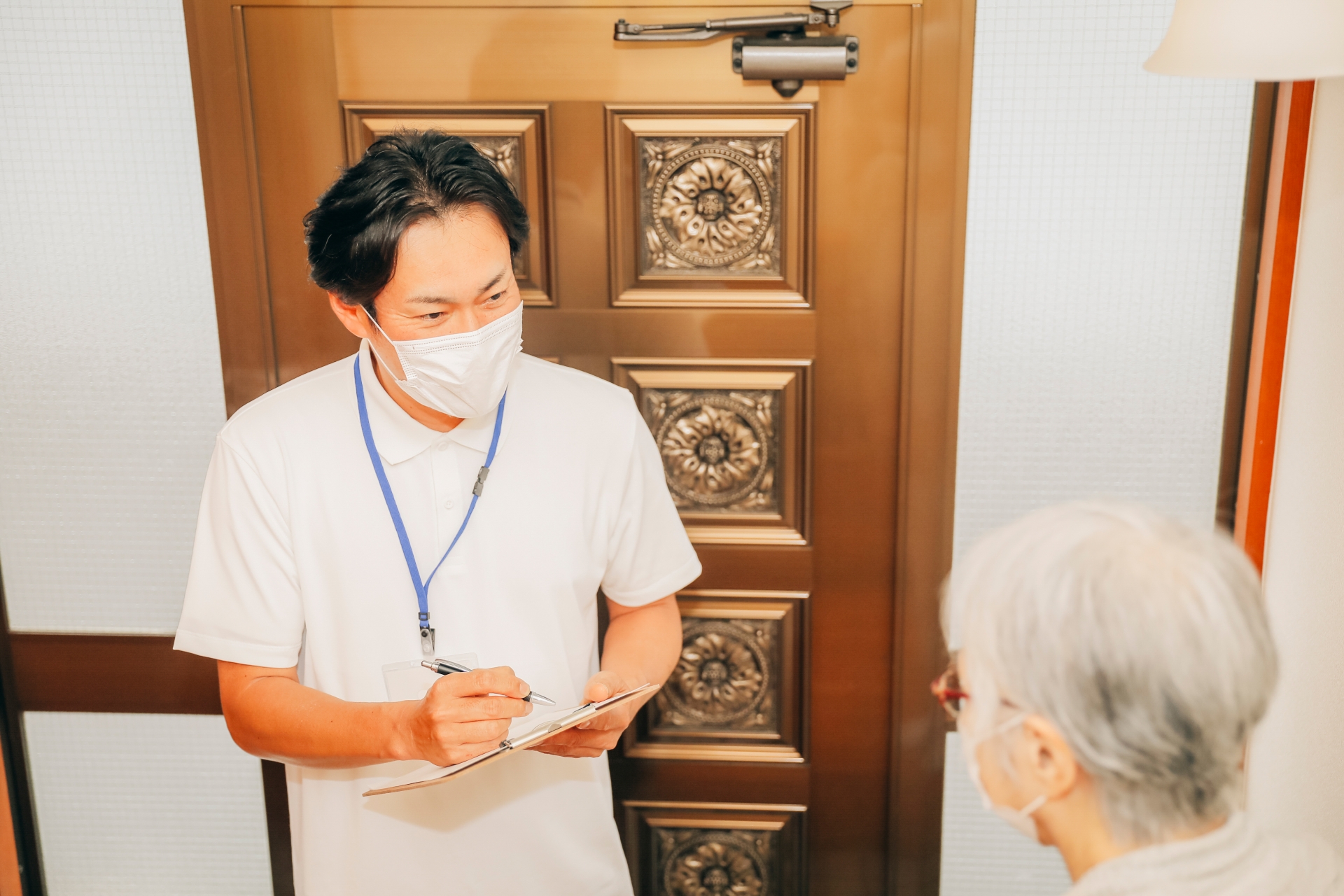 高齢者住宅に訪問する男性(書類・マスク)