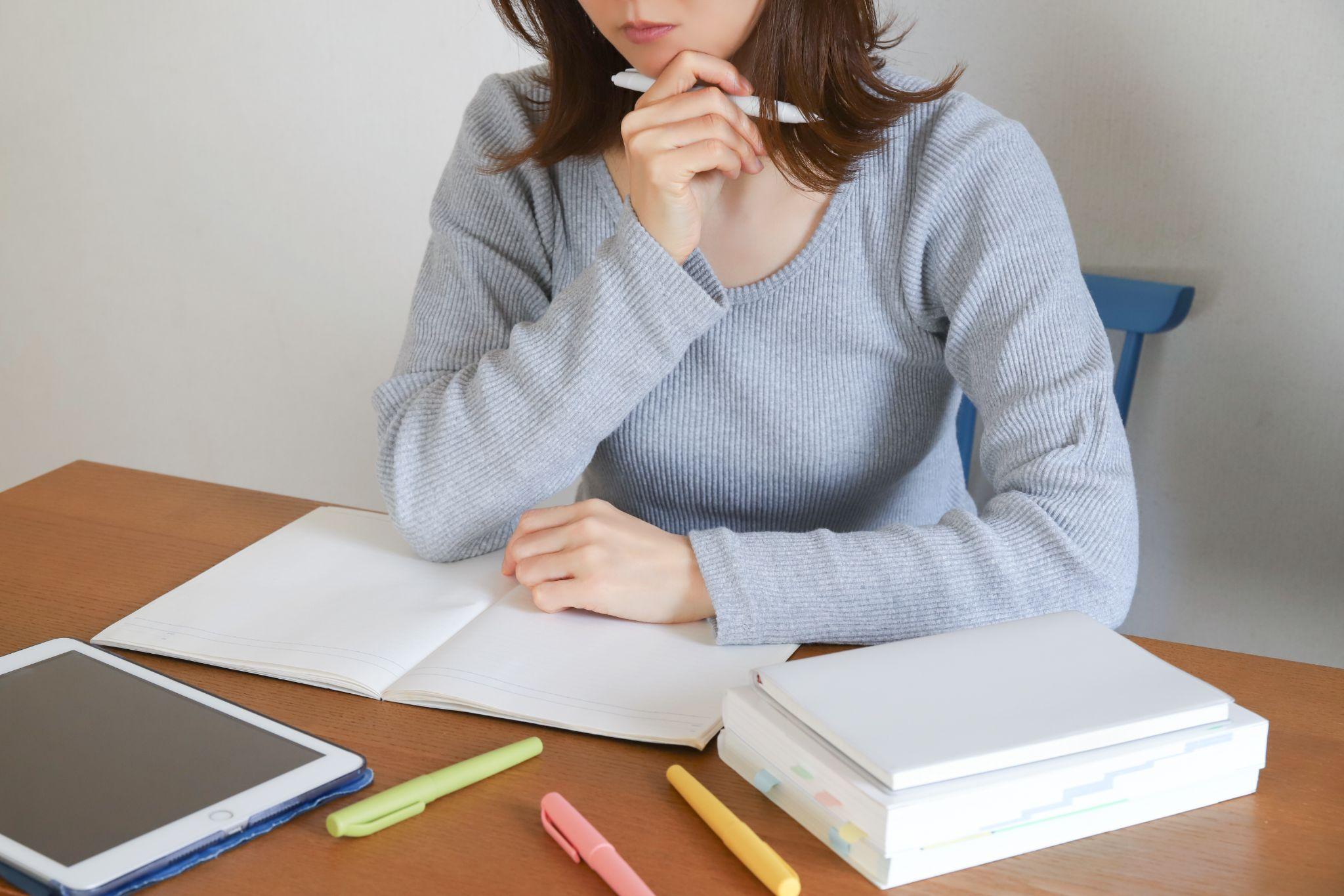 勉強中に考え込む女性とノートや参考書