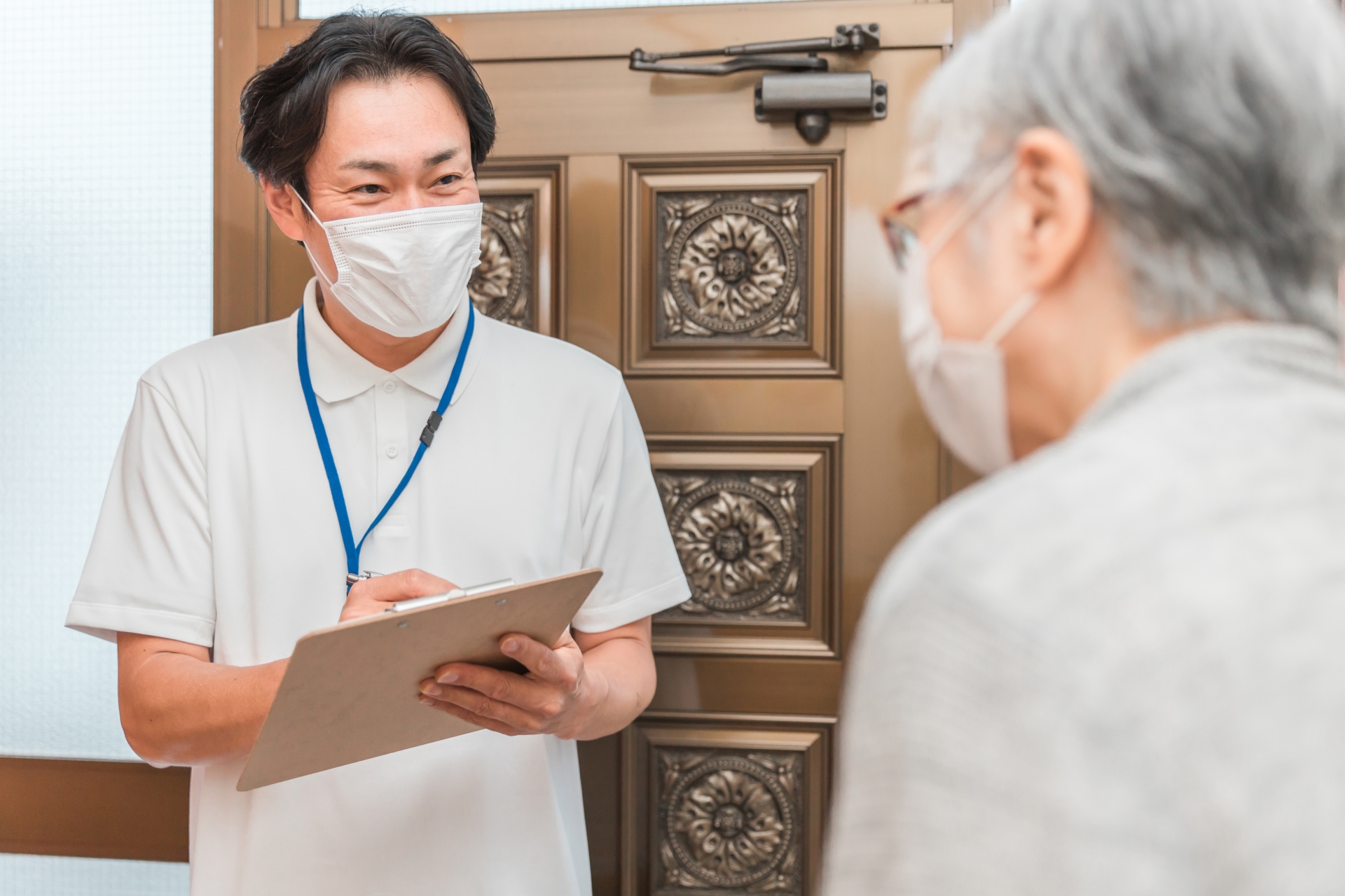 高齢者住宅に訪問する男性(書類・マスク)
