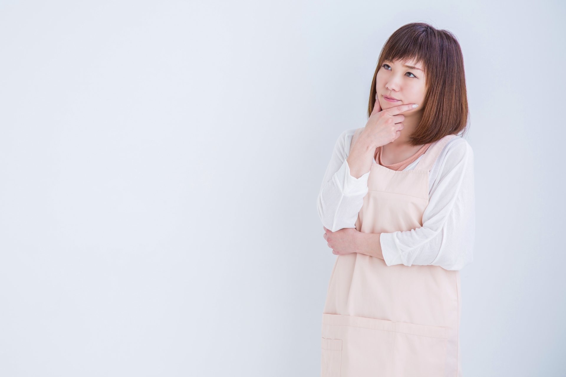 考えるエプロン姿の女性