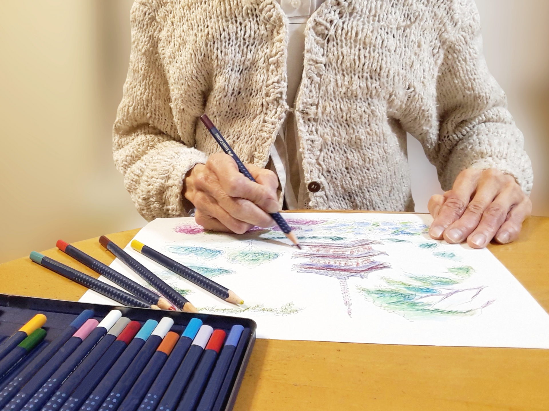 色鉛筆画を描く高齢女性の手
