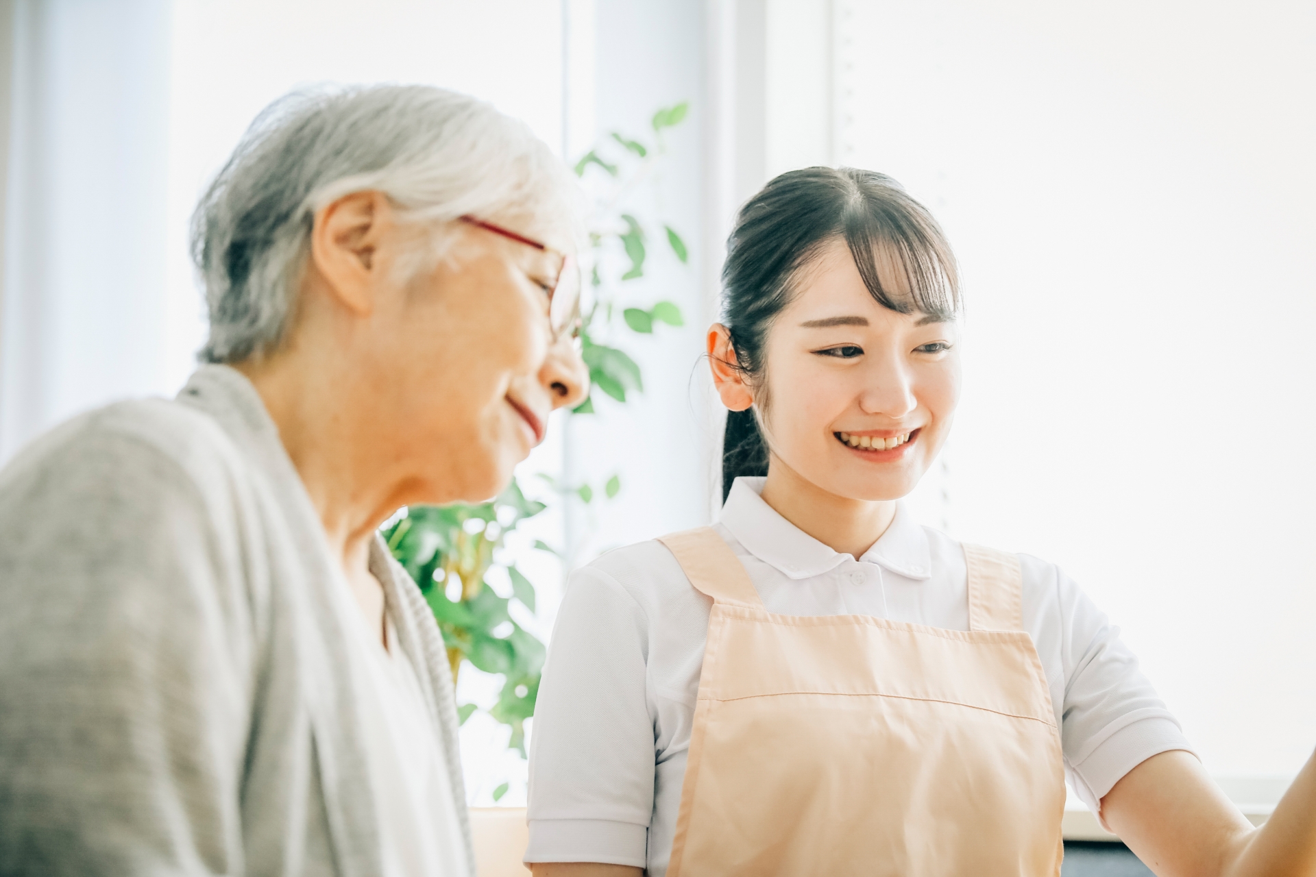 エプロン姿の女性スタッフと高齢者（笑顔）