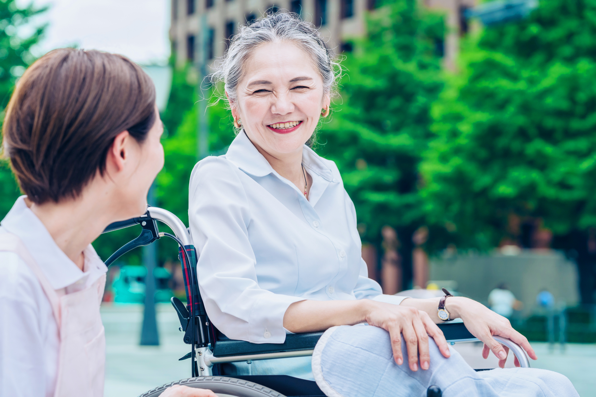 車イスに乗って、笑顔で話すシニア女性