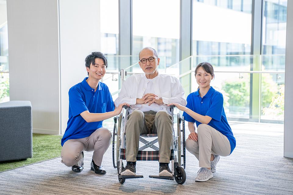 介護施設のシニア男性と男女のケアスタッフ