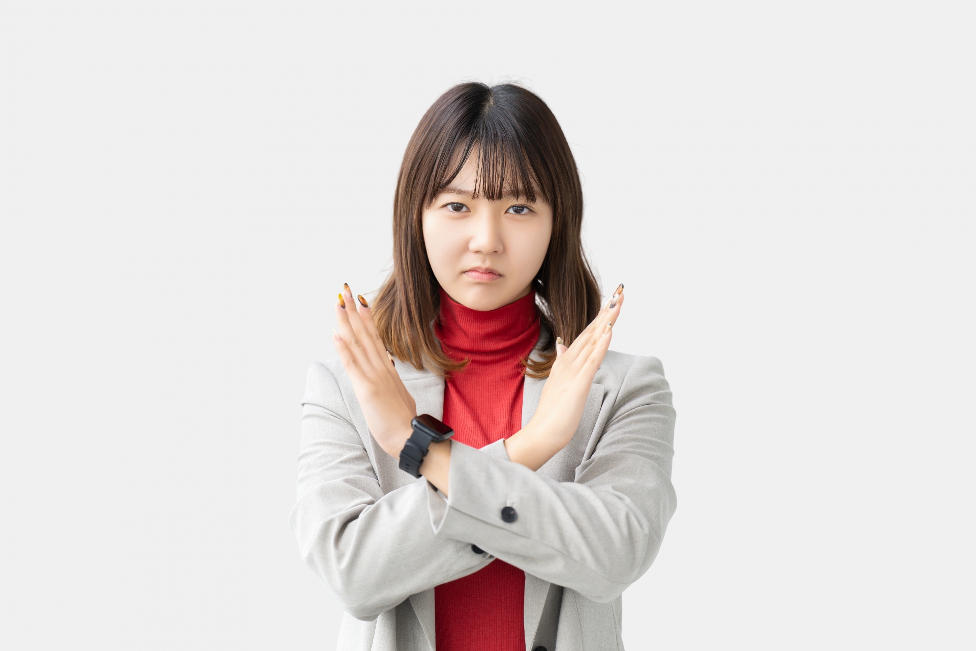 手でバツのポーズをする困った表情の女性