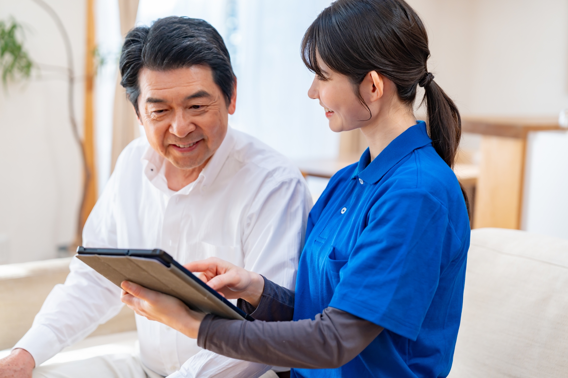 タブレットで説明を受ける男性と介護士