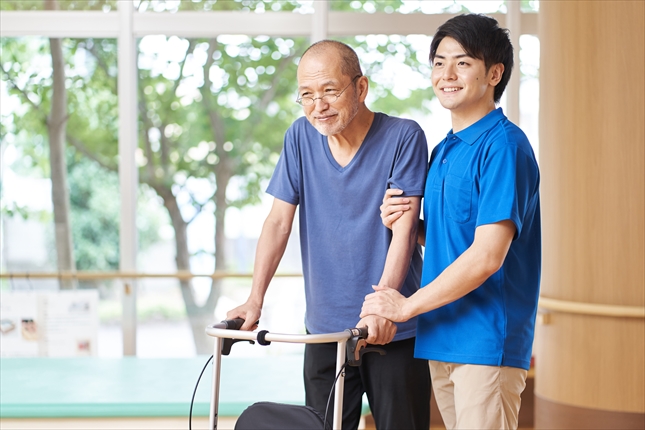 歩行介助をされながら歩く高齢者
